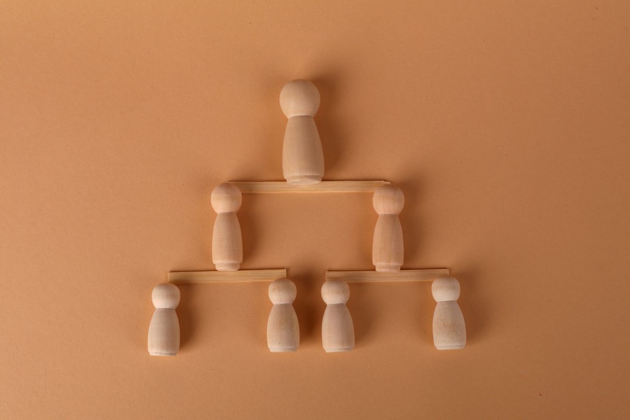 Wooden peg dolls arranged in a pyramid, symbolizing leadership and teamwork.